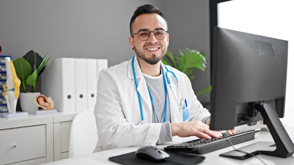 Wall Mural - Hispanic man doctor using computer working at the clinic