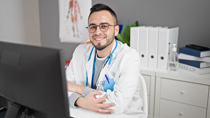 Wall Mural - Hispanic man doctor using computer working at the clinic