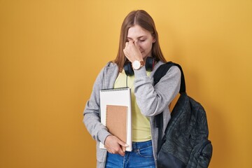 Canvas Print - Young caucasian woman wearing student backpack and holding books tired rubbing nose and eyes feeling fatigue and headache. stress and frustration concept.