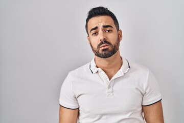 Canvas Print - Young hispanic man with beard wearing casual clothes over white background looking sleepy and tired, exhausted for fatigue and hangover, lazy eyes in the morning.