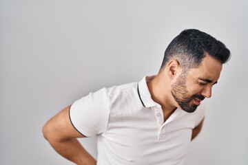 Poster - Young hispanic man with beard wearing casual clothes over white background suffering of backache, touching back with hand, muscular pain