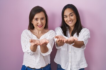 Canvas Print - Hispanic mother and daughter together smiling with hands palms together receiving or giving gesture. hold and protection