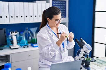 Sticker - Young hispanic woman scientist write on test tube working at laboratory