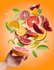 Wall Mural - Female hand and flying slices of orange lime, lemon, grapefruit and green mint leaves. Water splash. Fruit for juicing