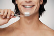 © gstockstudio - Close-up of young shirtless man holding toothbrush and smiling against grey background