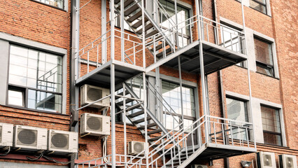 Poster - Fire Escape stairs on red brick classic building wall, Old Industrial building from red bricks with metal rain pipes
