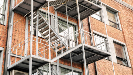 Poster - Fire Escape stairs on red brick classic building wall, Old Industrial building from red bricks with metal rain pipes