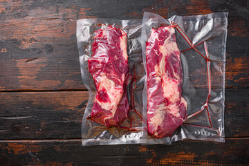 Wall Mural - Chuck roll  beef steak Vacuum packed meat on dark old wooden table, top view with space for text.