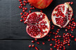 Ripe pomegranate with fresh juicy seeds, on black wooden table, top view