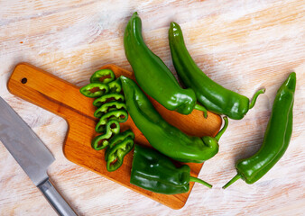 Wall Mural - Fresh green bell peppers with chopped slices on wooden cutting board. Healthy vegetarian ingredient