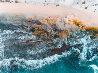Wall Mural - Aerial view of pink sandy beach with waves. Sunny day in summer with transparent tropical blue water. Summer seascape beautiful waves, blue sea water on a sunny day. Top view from drone. Sea aerial