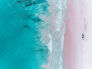 Wall Mural - Aerial view of beautiful tropical turquoise ocean sea waters with shallow waves on pink beach. Vibrant bright sunny day in summer wallpaper. Sandy pink sand beach, Seascape background. Coastal