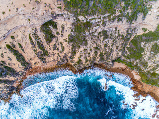 Wall Mural - Aerial top down view of cliffs and clear blue water. Ocean waves smashing on the cliffs as a background. Beautiful natural winter vacation holidays background. Wyadup Bay, Margaret River, Australia