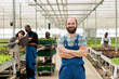 © DC Studio - Smiling farm worker in green bio eco friendly agriculture organic hydroponic greenhouse with group of farmers. Locally grown chemical free vegetable crops using recycled water and non-GMO fertilizer