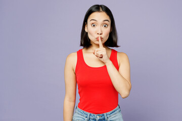 Wall Mural - Young secret woman of Asian ethnicity wear casual clothes red tank shirt say hush be quiet with finger on lips shhh gesture isolated on plain pastel light purple background studio. Lifestyle concept.