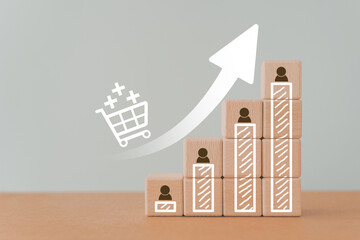 For customer loyalty increasing, growing graph and man icon on wooden cube blocks with white shopping cart above up arrow