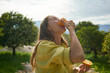 © Westend61 - Woman eating fresh juicy orange in orchard
