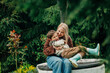 © Westend61 - Mother with son sitting together on well in garden