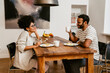 © Drobot Dean - Smiling couple having lunch together while sitting in kitchen