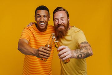 Wall Mural - Two happy men smiling at camera holding beer while standing isolated