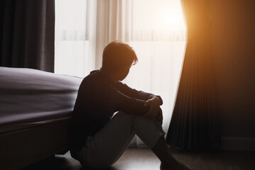 The young man was sitting in the bedroom. He was looking out the window and felt sorrowful feeling unhappy in personal life He has problems and fights with his girlfriend and tends to break up.