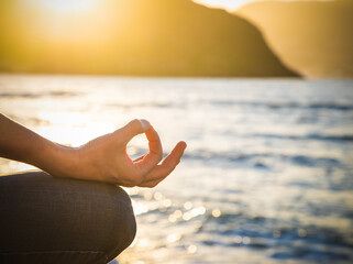 woman meditating by the sea at sunset