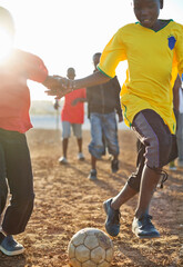 Wall Mural - Boys playing soccer together in dirt field