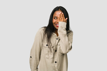 Wall Mural - Young Indian woman cut out isolated on white background having fun covering half of face with palm.