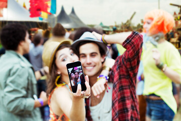 Wall Mural - Couple taking self-portrait with camera phone at music festival