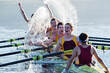 Rowing team splashing and celebrating in scull on lake