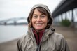 Medium shot portrait photography of a grinning mature girl wearing a lightweight windbreaker against a riverfront background. With generative AI technology
