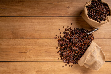 The picture of coffee beans stacked together on a wooden floor in a warm, light atmosphere, on a dark background, with copy space.