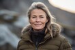 © Markus Schröder - Close-up portrait photography of a satisfied mature woman wearing a cozy winter coat against a serene rock garden background. With generative AI technology
