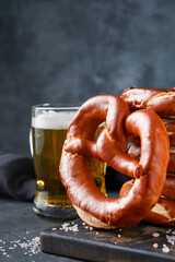 Wall Mural - Oktoberfest concept card. Traditional Bavarian pretzels with beer bottle mug on old dark black rustic background. Perfect for Octoberfest. Oktoberfest food menu.