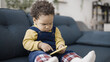 © Synthex - Serious African American baby looks bossy and funny while playing on a smartphone