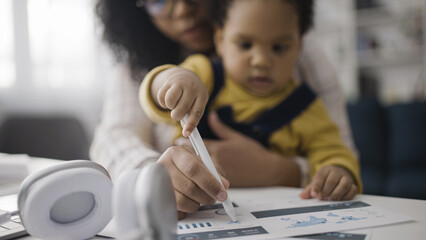 Baby drawing on business papers, sitting on mother's lap while she's working, unpaid parental leave