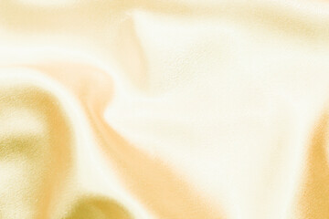 Yellow shiny texture of silk satin satin with folds.