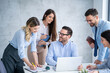 © Bojan - Group of business professionals gather around a desk engaging in a focused discussion holding notebooks and documents during meeting with their executive director at office.