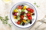 Fototapeta Tematy - Greek salad. Vegetable salad with feta cheese, tomato, olives, cucumber, red onion and olive oil. Healthy vegetarian mediterranean diet food. Top view