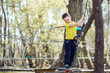 © ADDICTIVE STOCK - Happy boy standing on rope bridge in park