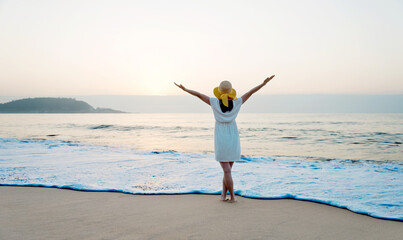 Poster - Happy woman standing on the beach with hands up.