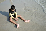 Fototapeta Morze - Asian boy playing with sand at the beach in summer