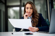 © bnenin - A serious female employee reading a business document at the office.