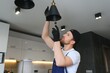 © Serhii - A male electrician changes the light bulbs in the ceiling light. men's household duties. care of electrical appliances at home