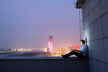 Businessman sitting on the rooftop and using laptop