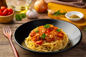 Wall Mural - Spaghetti with canned tuna fish in tomato sauce, pasta with a meat based bolognese tomatoes,served in black plate