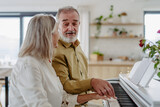 Beautiful eldery couple playing a piano at home