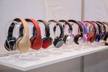 Colorful wireless headphones in row at electronic store, exhibition. Entertainment, technology, device, sale and multimedia concept