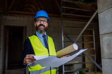 Wall Mural - Mature businessman controlling blueprints from unfinished house.