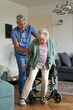 © Halfpoint - Caregiver helping senior woman to stand from her wheelchair in her home.
